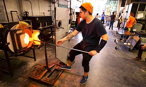 Student pulling glass work from furnace